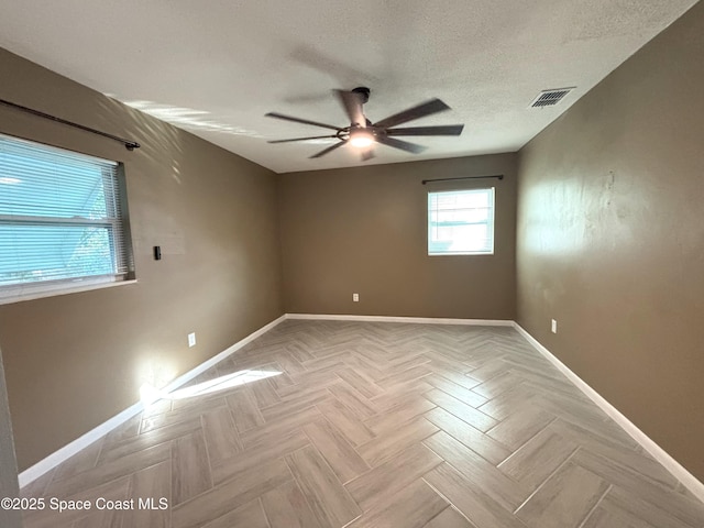 unfurnished room with ceiling fan, light parquet flooring, and a textured ceiling