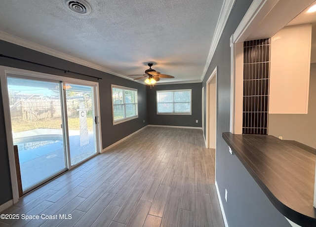 unfurnished living room with ceiling fan, ornamental molding, light hardwood / wood-style floors, and a textured ceiling