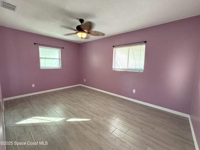 unfurnished room with ceiling fan and a textured ceiling