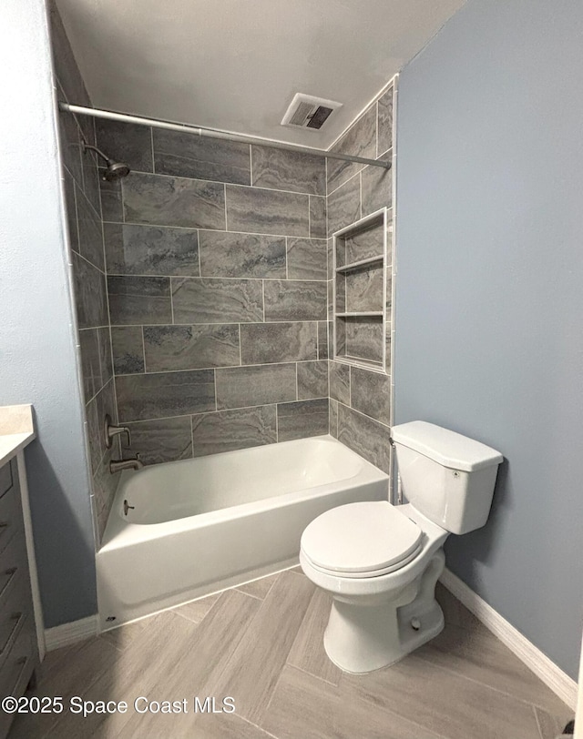 full bathroom with vanity, tiled shower / bath, and toilet