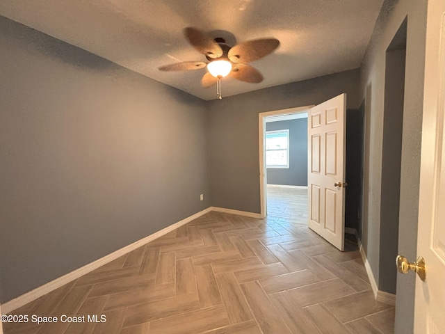 empty room featuring parquet floors, a textured ceiling, and ceiling fan