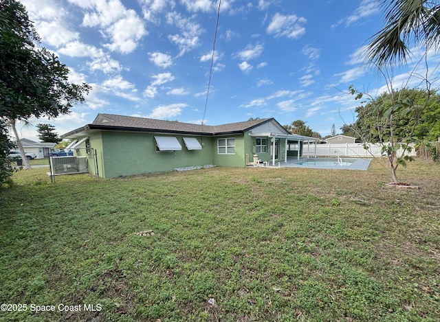 back of property featuring a fenced in pool, a patio area, and a lawn