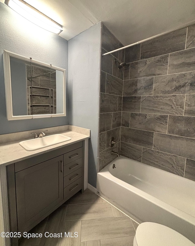 full bathroom with tiled shower / bath, vanity, and toilet