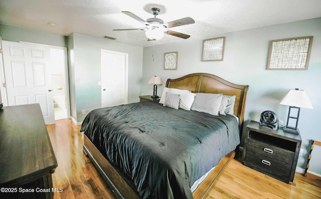 bedroom with a textured ceiling, ceiling fan, connected bathroom, and hardwood / wood-style flooring