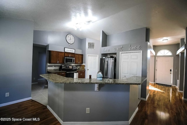 kitchen featuring tasteful backsplash, vaulted ceiling, stone counters, a kitchen breakfast bar, and stainless steel appliances