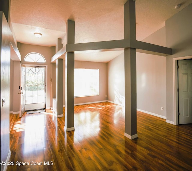 entrance foyer featuring dark wood-type flooring, a textured ceiling, and vaulted ceiling