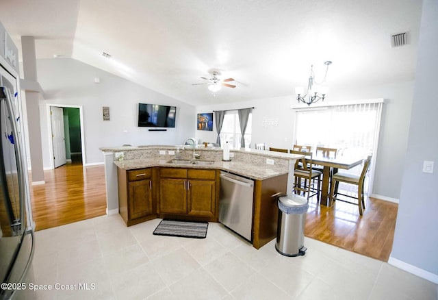 kitchen with an island with sink, stainless steel dishwasher, hanging light fixtures, and sink