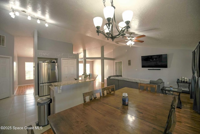 dining area with lofted ceiling, ceiling fan with notable chandelier, and a textured ceiling