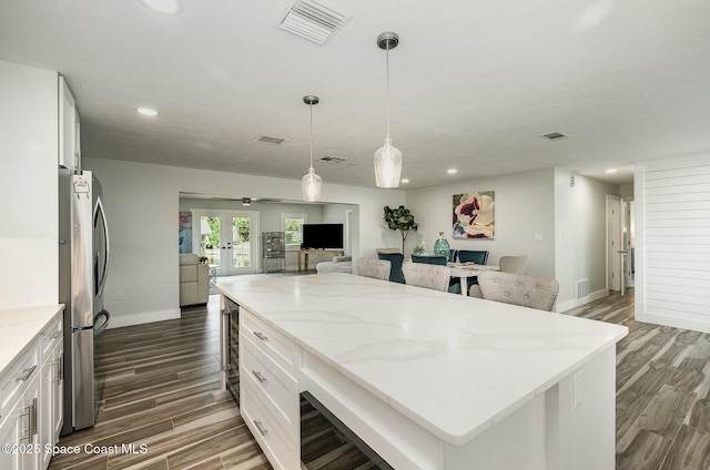 kitchen featuring white cabinets, french doors, stainless steel fridge, a kitchen island, and pendant lighting