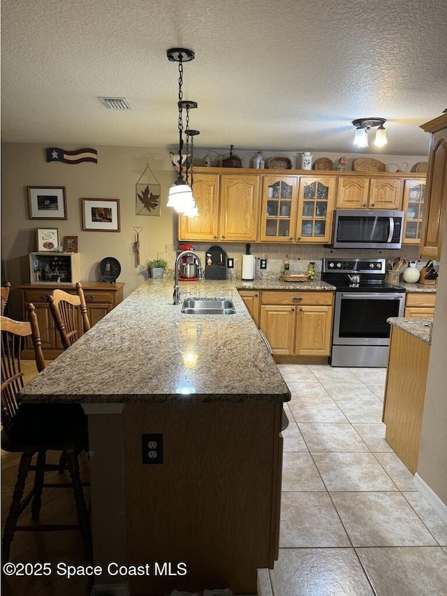 kitchen with kitchen peninsula, stainless steel appliances, hanging light fixtures, a textured ceiling, and sink