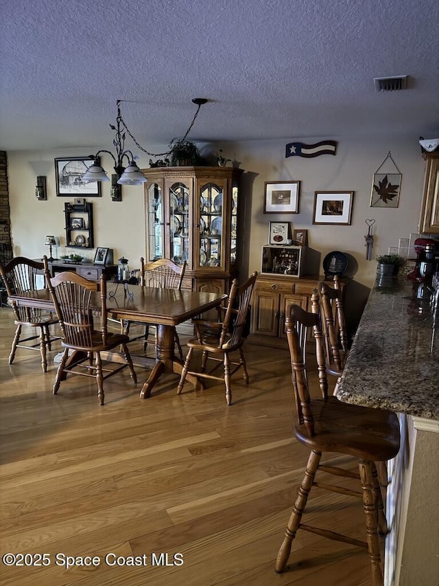 dining area with a textured ceiling, an inviting chandelier, and hardwood / wood-style floors