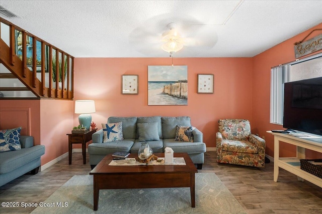 living room with a textured ceiling, ceiling fan, and hardwood / wood-style flooring