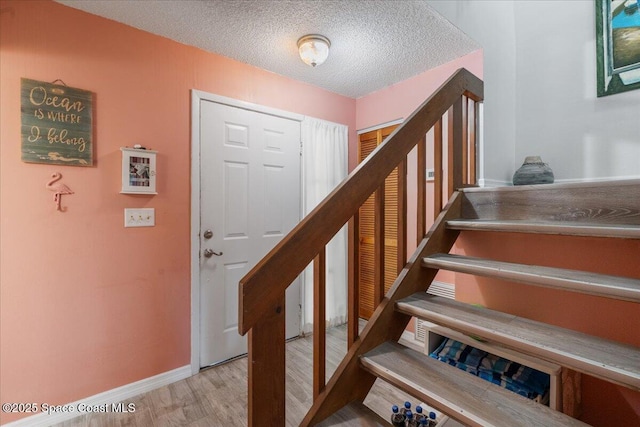 staircase featuring wood-type flooring and a textured ceiling