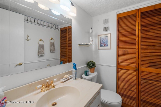 bathroom with toilet, vanity, and a textured ceiling