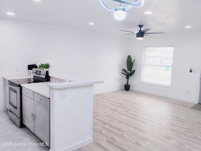 kitchen with ceiling fan, kitchen peninsula, stainless steel electric range oven, and light wood-type flooring