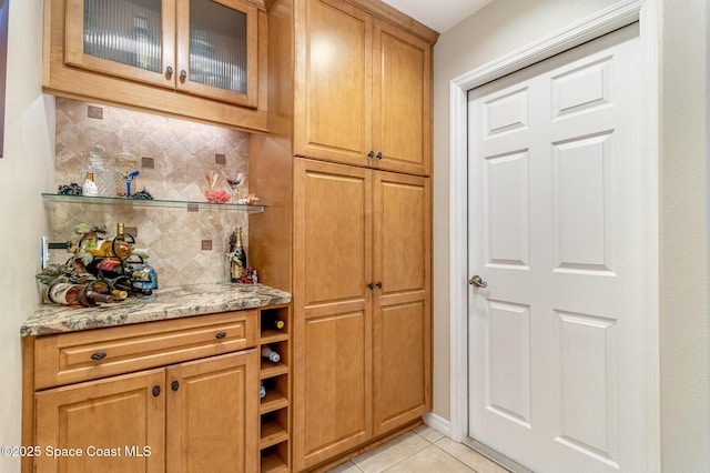 bar with light tile patterned floors, decorative backsplash, and light stone countertops