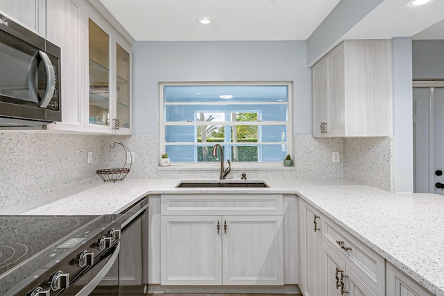 kitchen with white cabinets, range with electric stovetop, backsplash, and sink