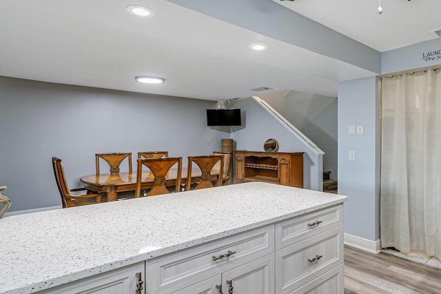 kitchen with light stone counters, white cabinets, and light hardwood / wood-style floors