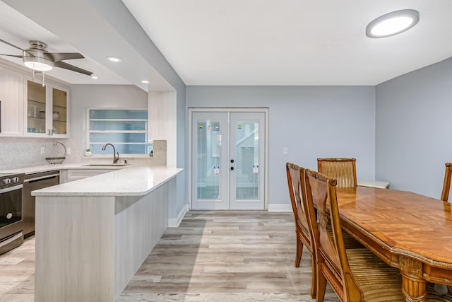 kitchen with sink, white cabinets, ceiling fan, light wood-type flooring, and kitchen peninsula