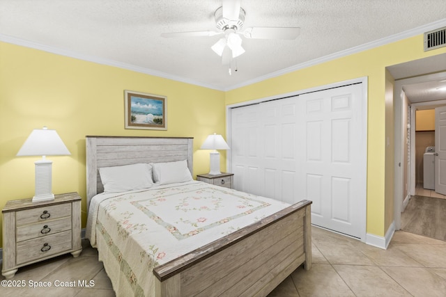 bedroom with a textured ceiling, washer / clothes dryer, a closet, ceiling fan, and crown molding