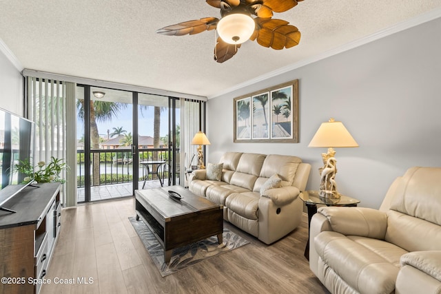 living room with light hardwood / wood-style flooring, a water view, a textured ceiling, expansive windows, and ornamental molding