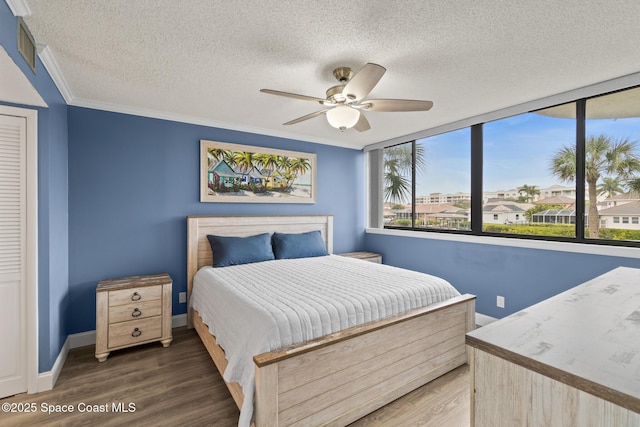 bedroom featuring a textured ceiling, dark hardwood / wood-style floors, ceiling fan, and ornamental molding