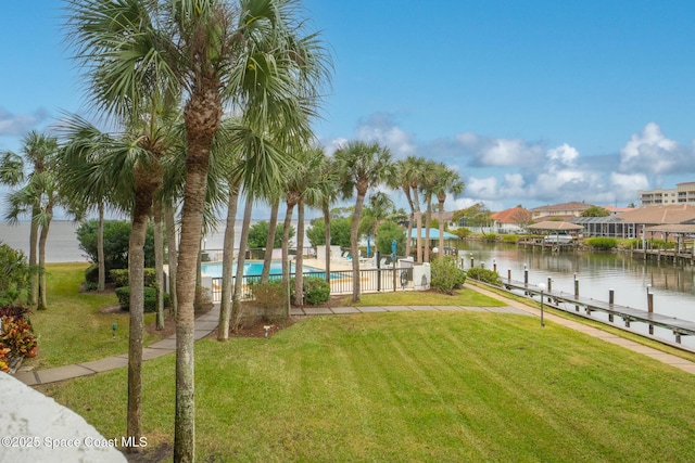 exterior space with a lawn, a pool, a boat dock, and a water view