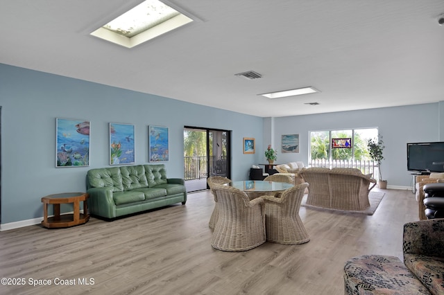 living room with a skylight and light wood-type flooring