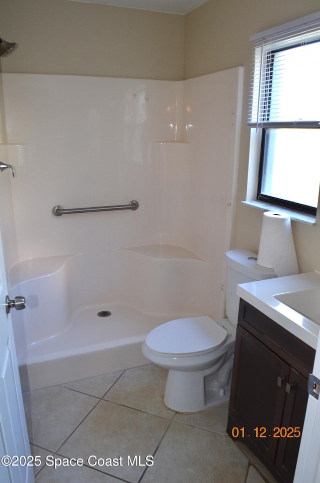 bathroom with a shower, toilet, vanity, and tile patterned flooring