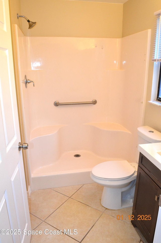 bathroom featuring toilet, a shower, tile patterned floors, and vanity