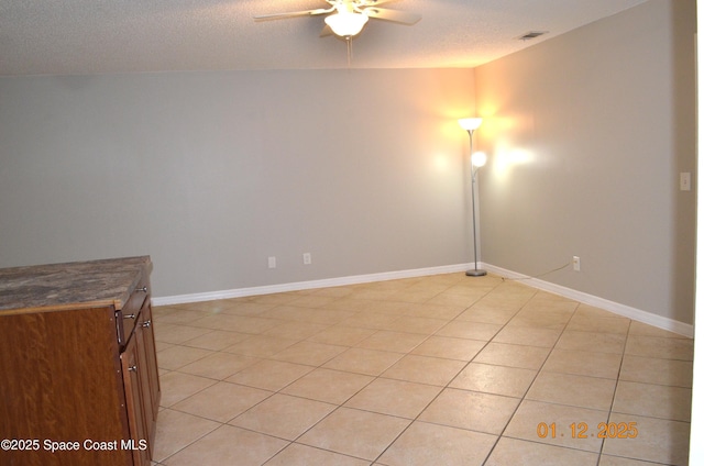 tiled empty room with a textured ceiling and ceiling fan