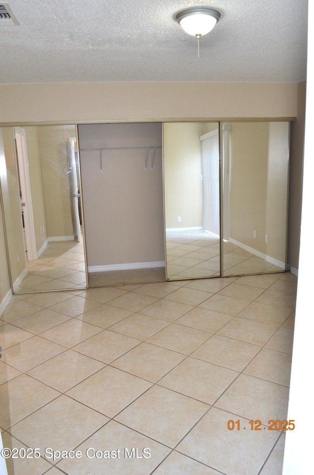 unfurnished bedroom with a textured ceiling, a closet, and light tile patterned floors