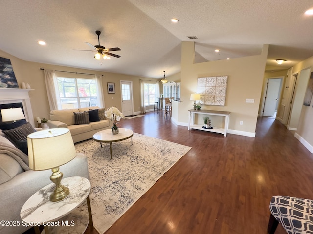 living room with dark hardwood / wood-style flooring, lofted ceiling, ceiling fan, and a textured ceiling