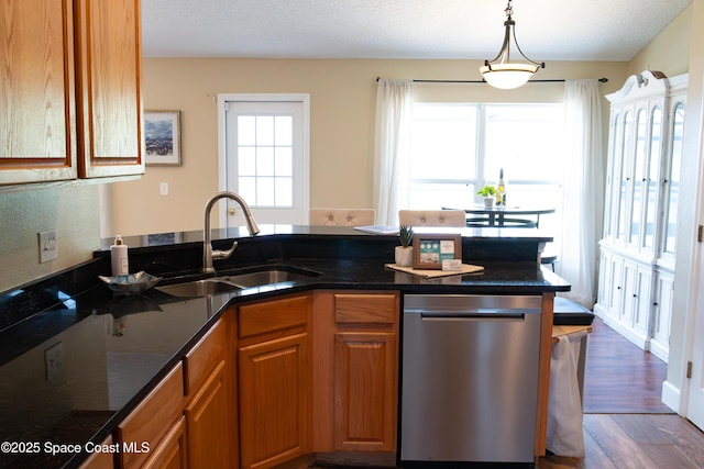 kitchen with dark stone countertops, sink, stainless steel dishwasher, and dark wood-type flooring