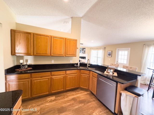 kitchen featuring sink, a textured ceiling, kitchen peninsula, dishwasher, and light hardwood / wood-style floors