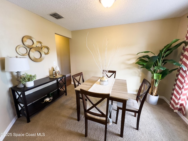 carpeted dining room with a textured ceiling