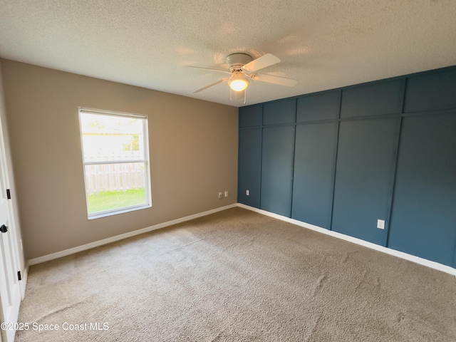 empty room with light carpet, a textured ceiling, and ceiling fan