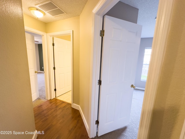 corridor with hardwood / wood-style floors and a textured ceiling