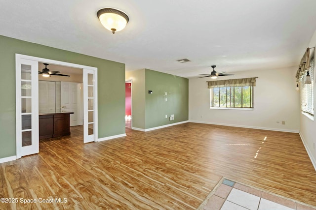 unfurnished living room featuring ceiling fan, french doors, and light hardwood / wood-style flooring