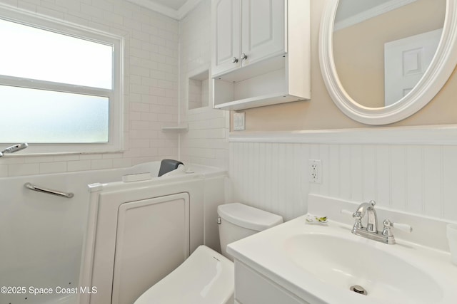 bathroom with a tub to relax in, toilet, ornamental molding, and vanity