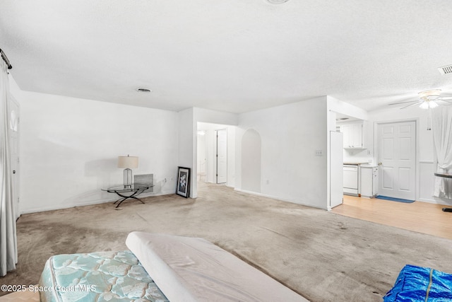 carpeted living room featuring a textured ceiling and ceiling fan