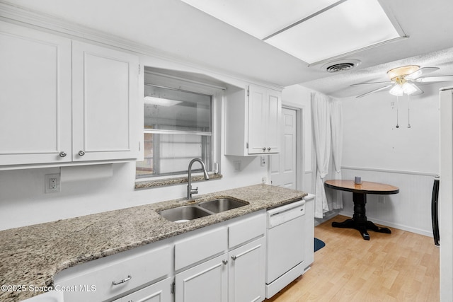 kitchen featuring white dishwasher, sink, white cabinetry, and ceiling fan