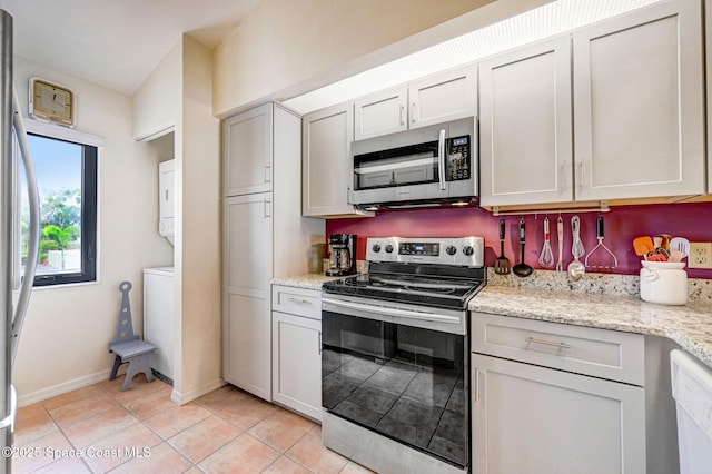 kitchen with white cabinetry, light tile patterned floors, light stone counters, and appliances with stainless steel finishes