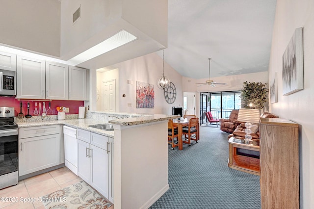 kitchen featuring appliances with stainless steel finishes, light stone countertops, kitchen peninsula, ceiling fan, and white cabinets