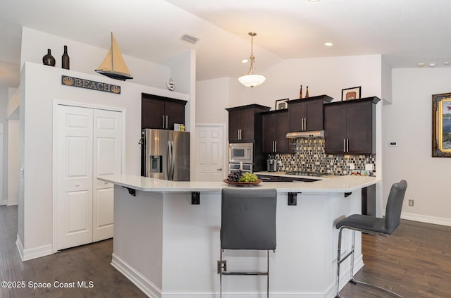 kitchen with a kitchen breakfast bar, dark hardwood / wood-style flooring, decorative backsplash, lofted ceiling, and stainless steel appliances