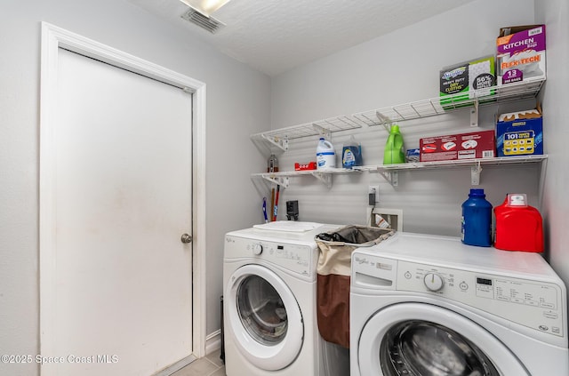 laundry area featuring washing machine and dryer, a textured ceiling, and light tile patterned flooring