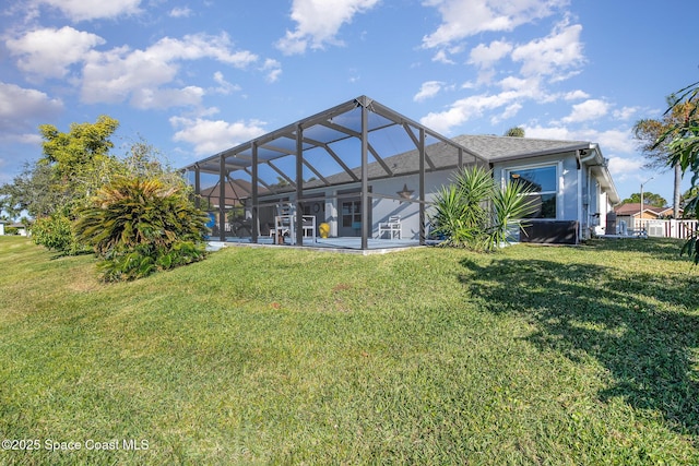 back of property with glass enclosure, a yard, and a patio