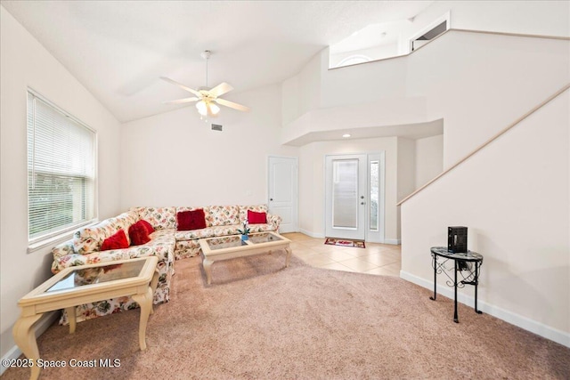 carpeted living room featuring ceiling fan and a towering ceiling