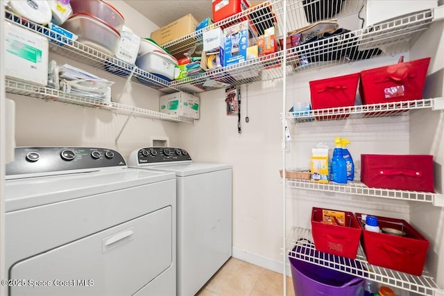 clothes washing area featuring washing machine and dryer and light tile patterned flooring