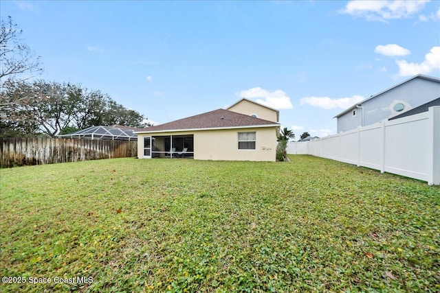 rear view of property featuring a sunroom and a yard